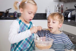 Children eating cookie dough from a bowl